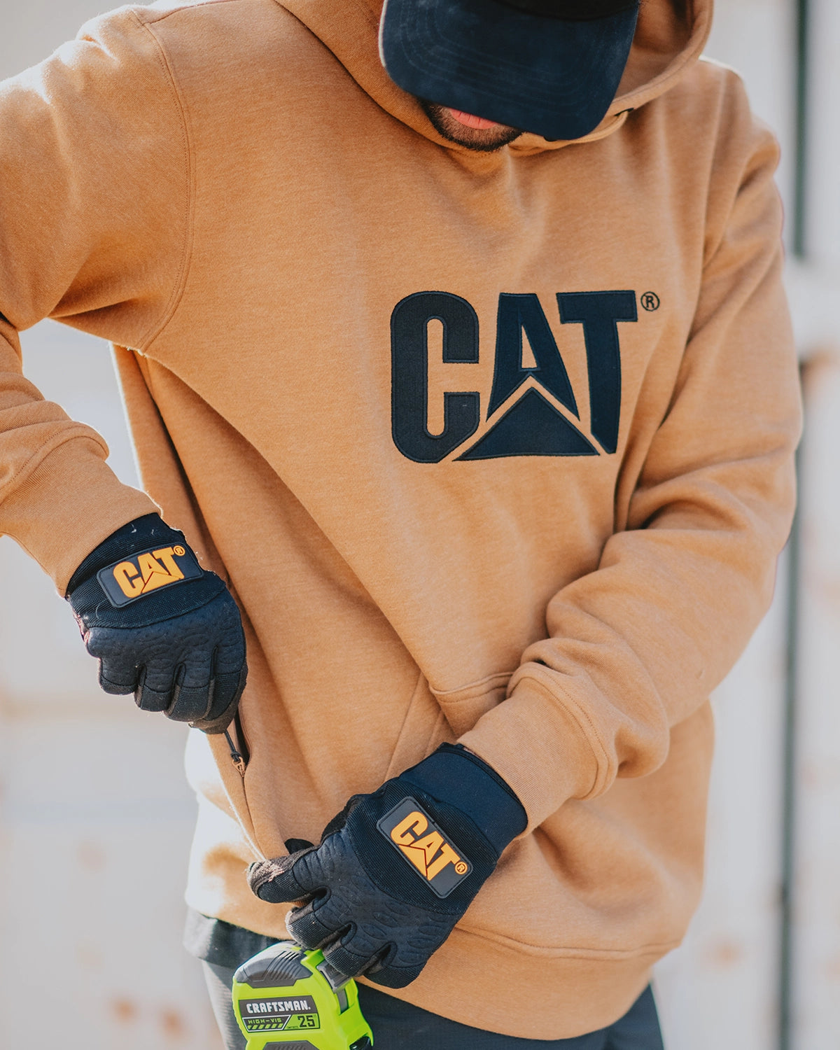 CAT workwear men's heavyweight trademark hoodie bronze on model with side zip pocket