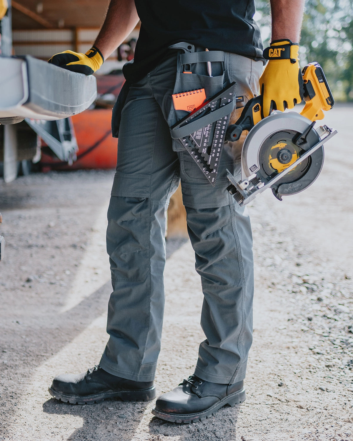 CAT workwear men's trademark utility work pant dark shadow on model holding a circular saw
