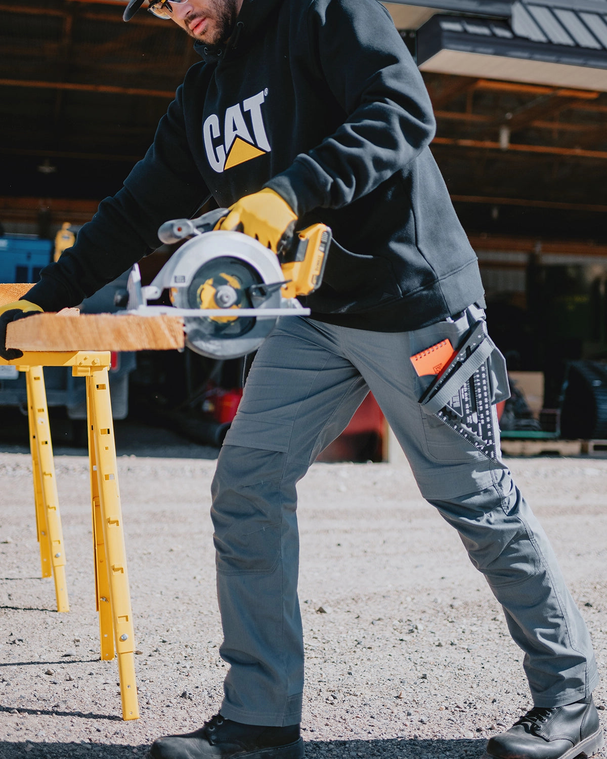 CAT workwear men's trademark utility work pant dark shadow on model using the circular saw