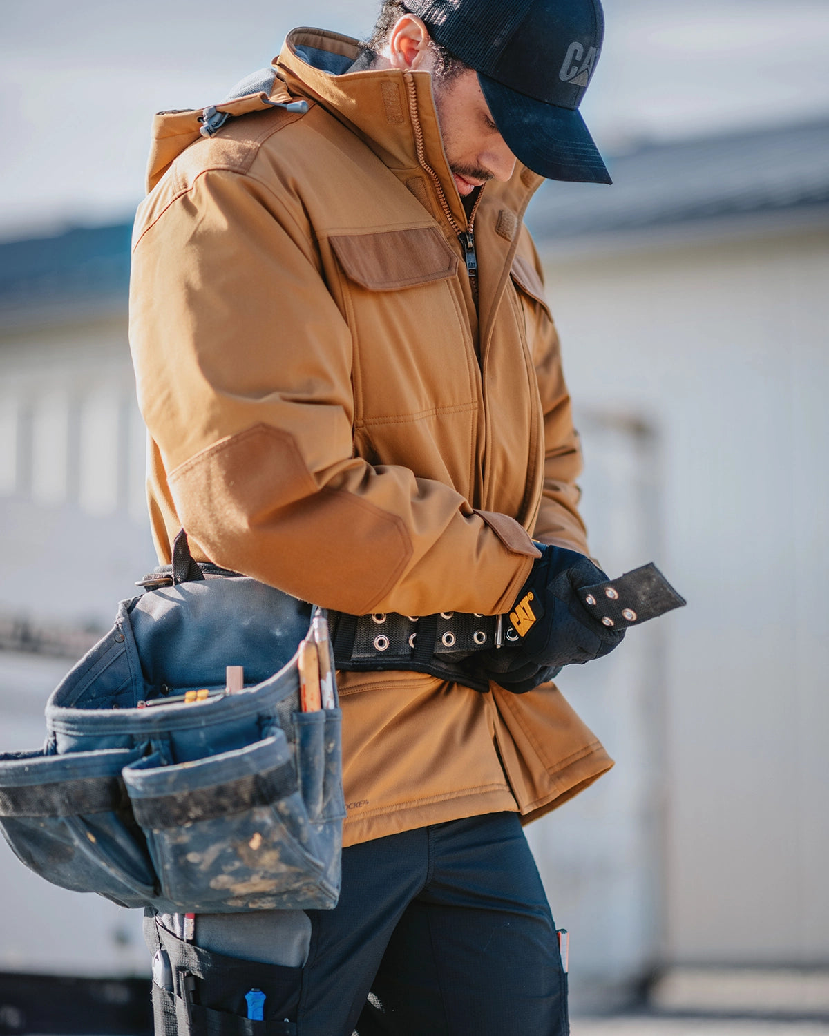 CAT workwear men's tradesman utility jacket in bronze on model with utility belt