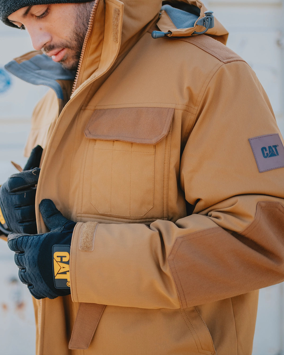 CAT workwear men's tradesman utility jacket in bronze on model zipping up the jacket